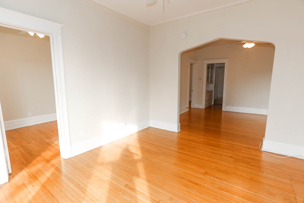 an empty living room with wood floors and white walls