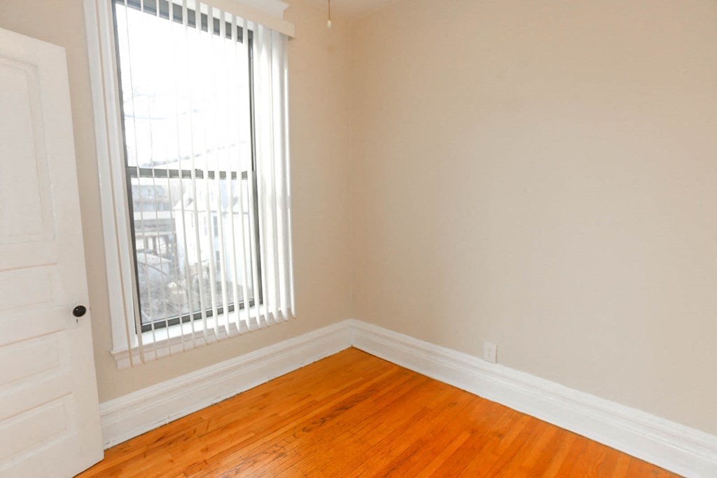 an empty room with wooden floors and a window