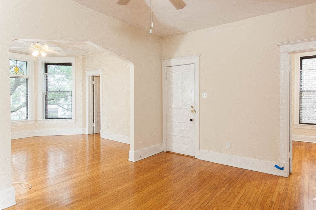 an empty living room with wood floors and a white door