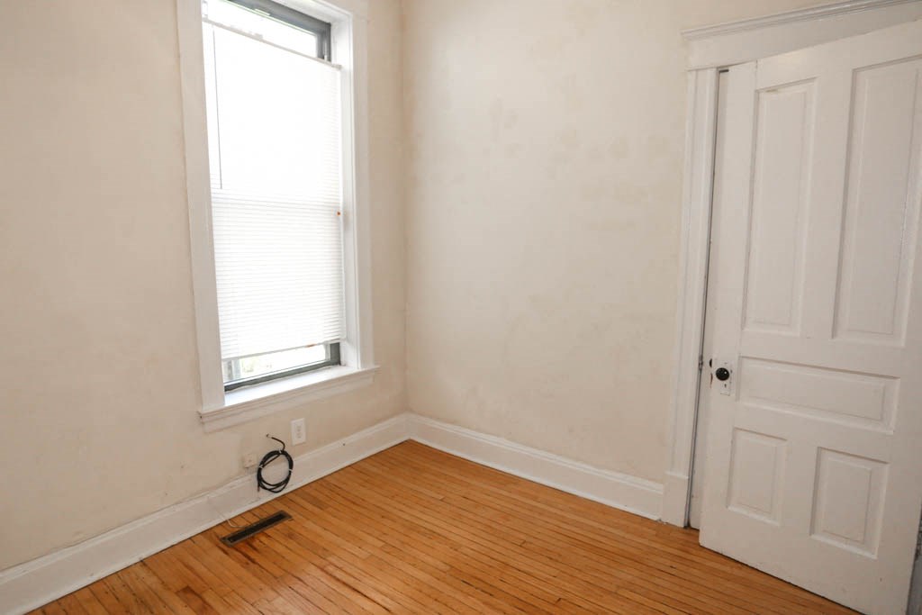 a room with a wooden floor and a window and a white door