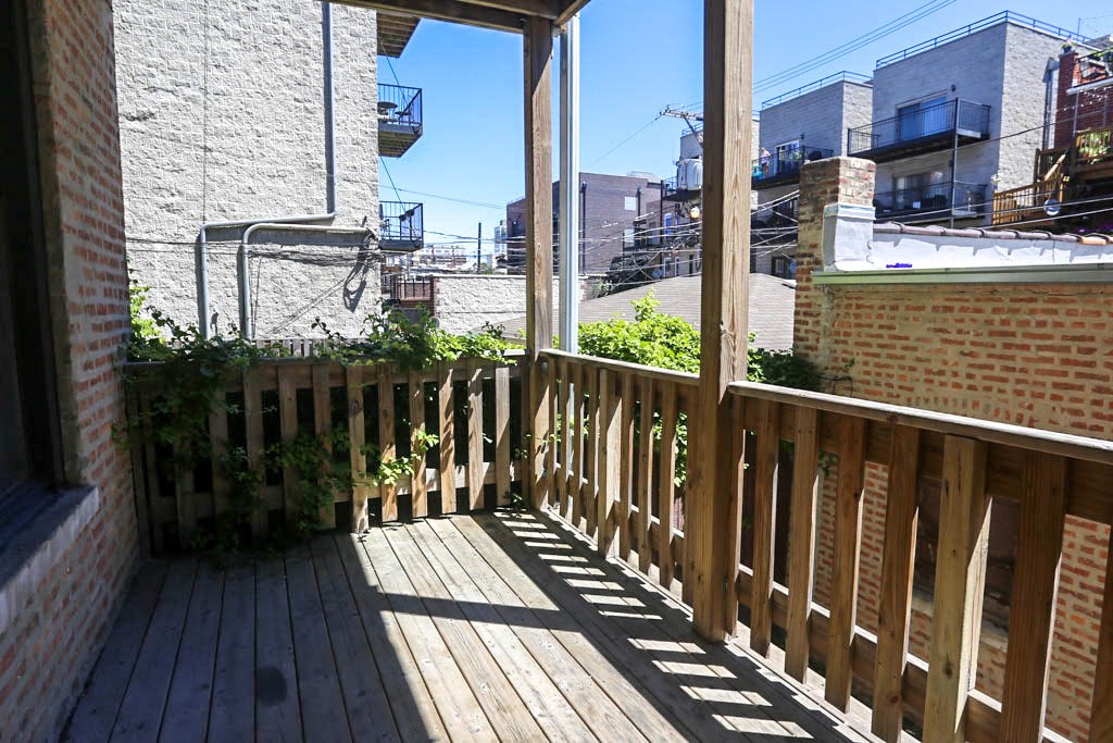 a balcony with a wooden floor and a brick building