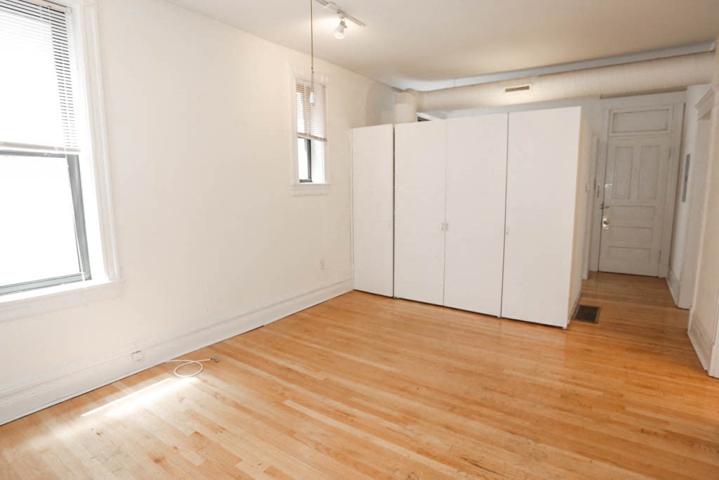 an empty room with white cabinets and a wood floor