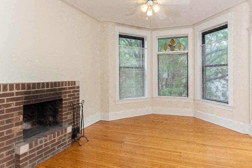 a living room with a brick fireplace and a wooden floor