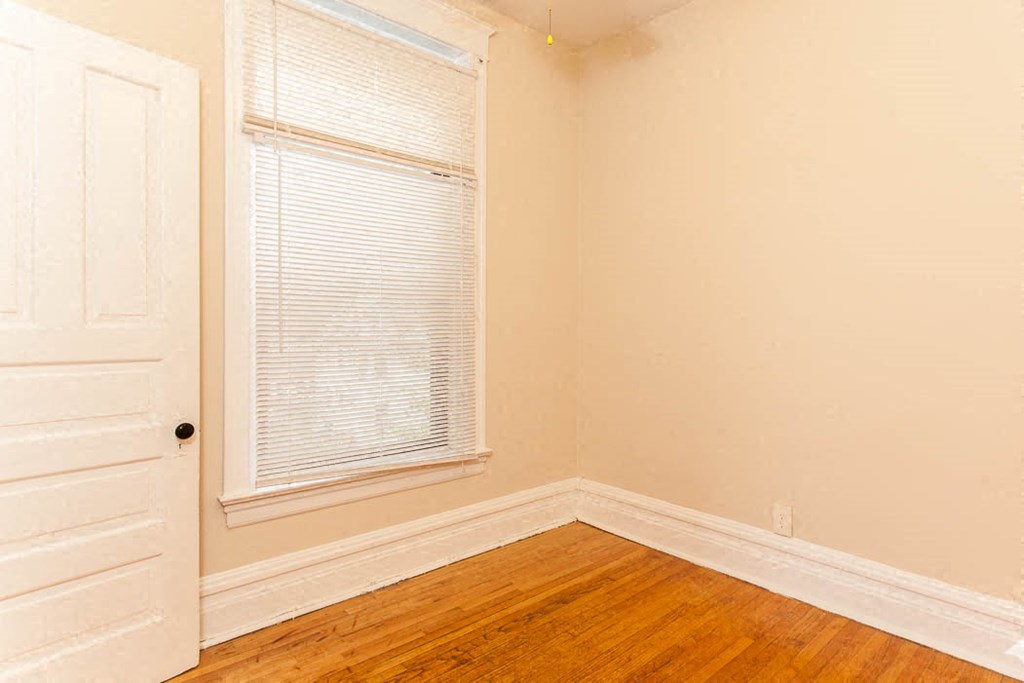 a room with a wooden floor and a window and a white door
