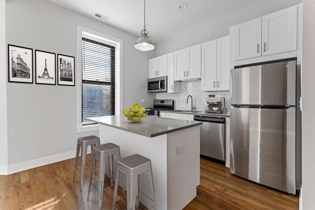 a kitchen with stainless steel appliances and a bar with three stools