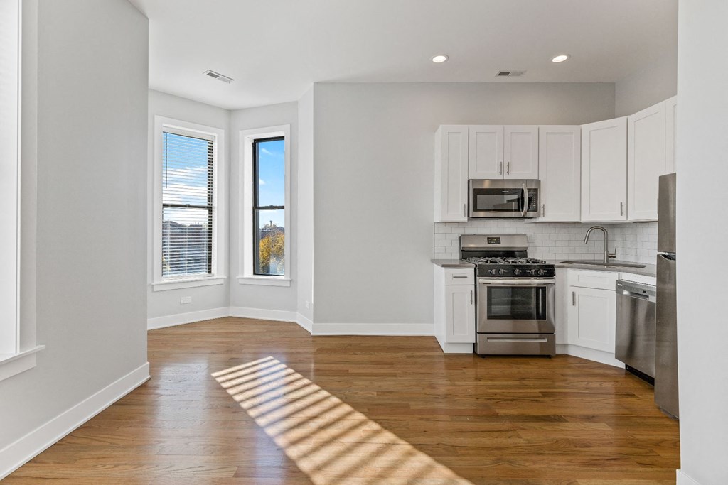 an empty kitchen with stainless steel appliances and white cabinets
