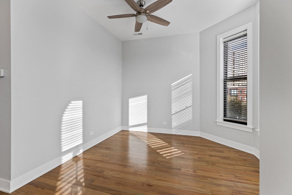 an empty living room with wood floors and a ceiling fan