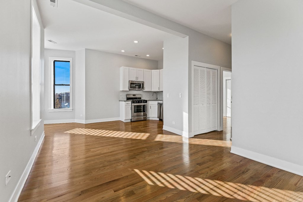 a living room and kitchen with white walls and wood floors