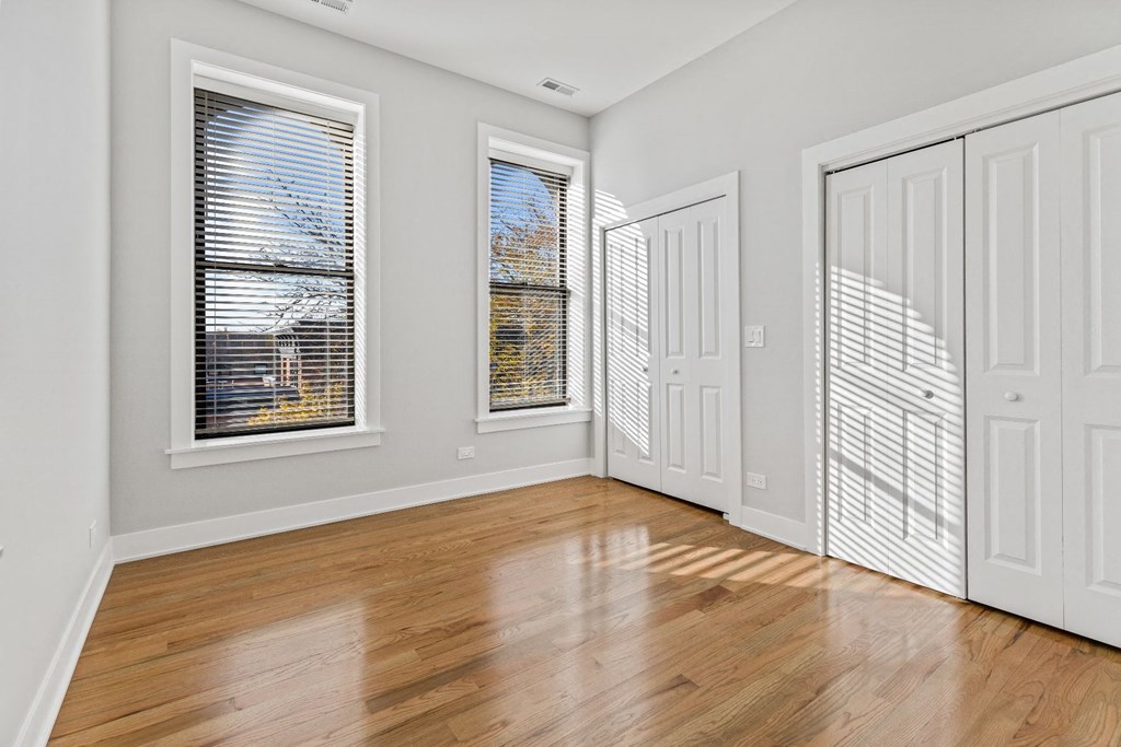 an empty living room with wood floors and white doors