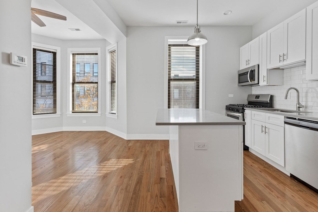 an empty kitchen with white cabinets and a counter top