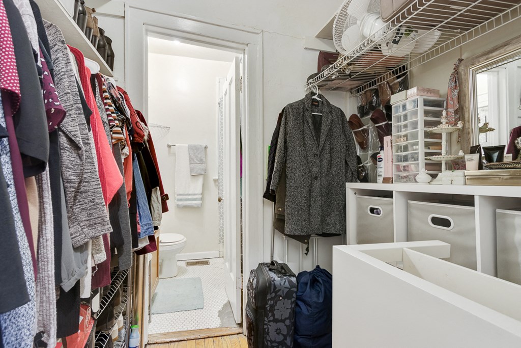 a small bathroom with a closet and a rack of clothes
