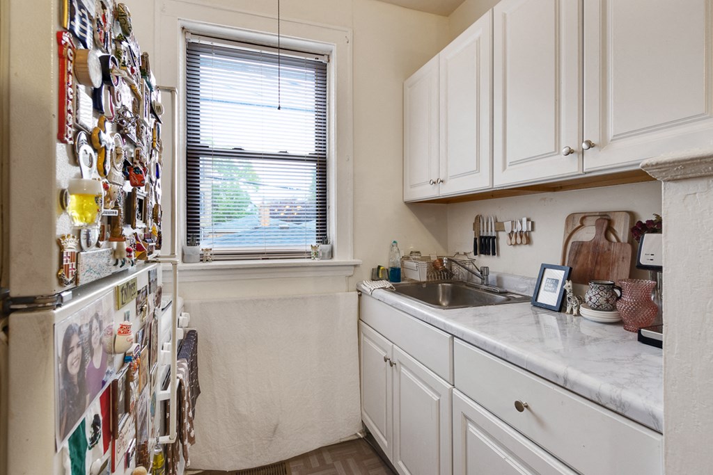 a kitchen with white cabinets and a refrigerator and a sink