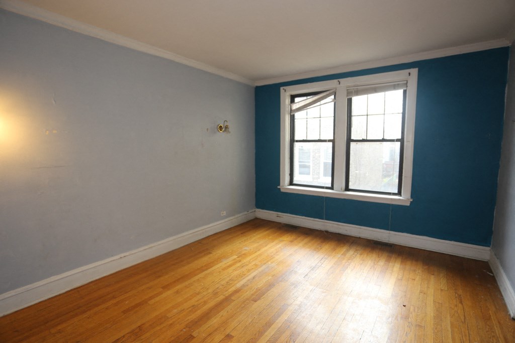 an empty room with blue walls and a window and wooden floors