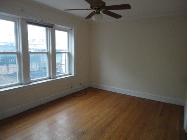 an empty room with a ceiling fan and three windows