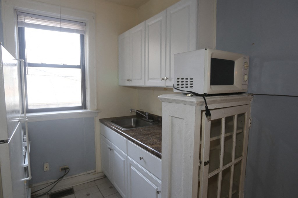an empty kitchen with a microwave on top of a refrigerator