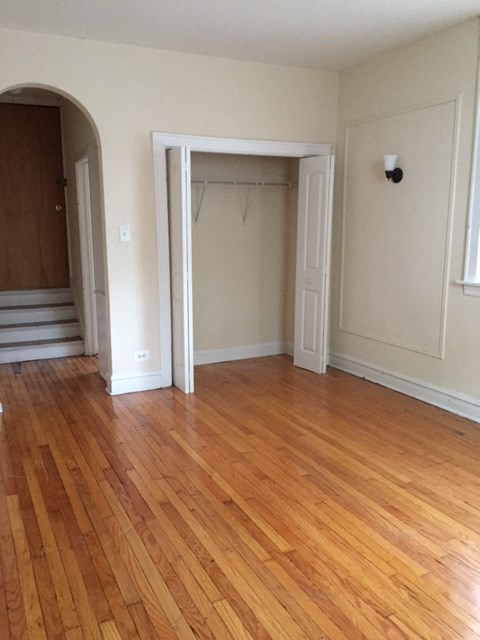 an empty living room with a hard wood floor and a closet