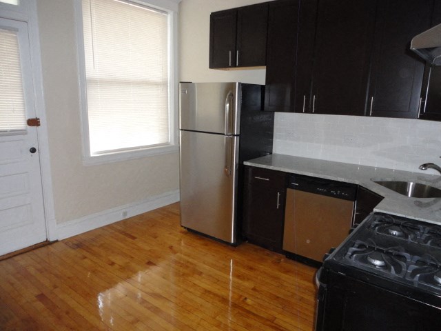 a kitchen with a stainless steel refrigerator and a wooden floor