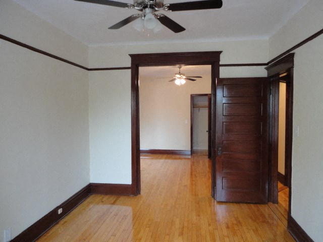 an empty living room with wooden floors and a ceiling fan