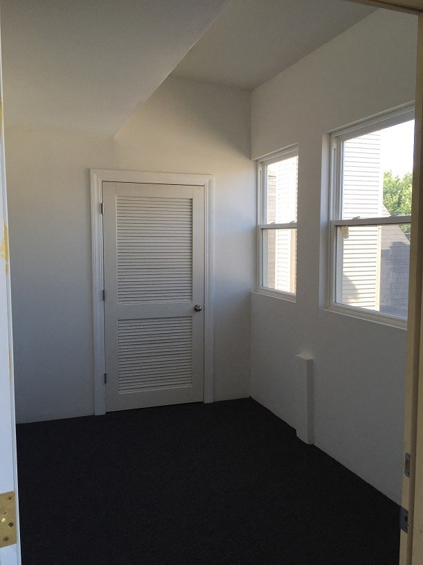 a small room with a door and two windows