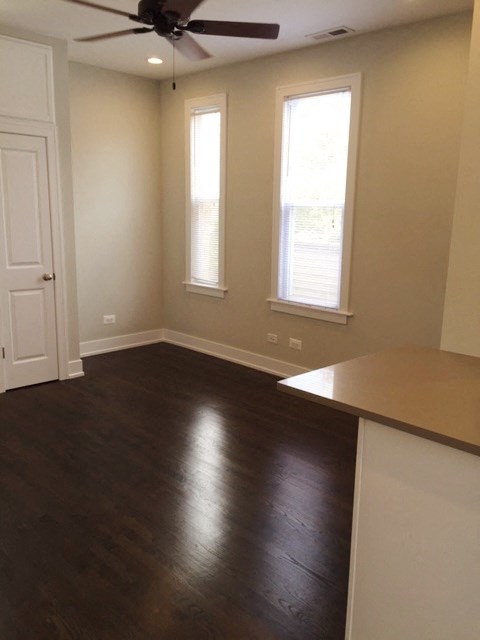 an empty living room with wooden floors and a ceiling fan