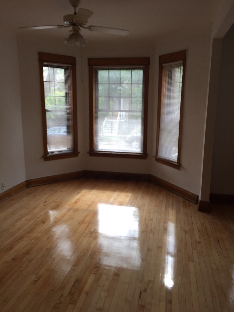 an empty living room with wood floors and three windows