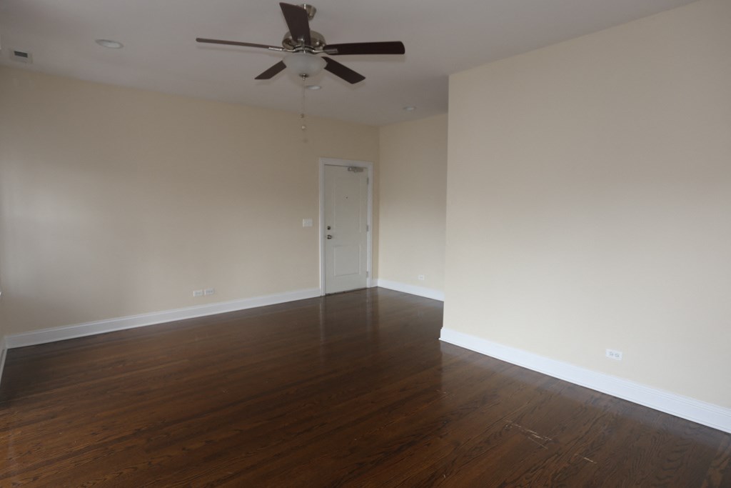 an empty living room with wooden floors and a ceiling fan