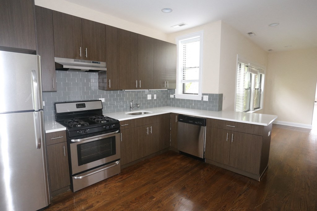 an empty kitchen with wooden floors and stainless steel appliances