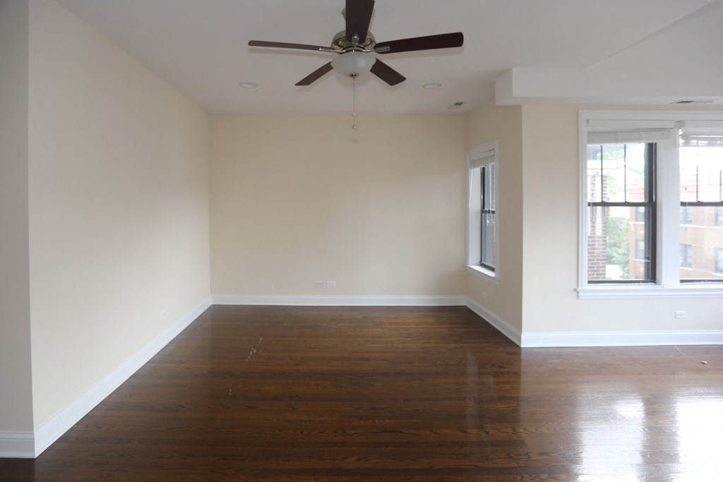 an empty living room with wood floors and a ceiling fan