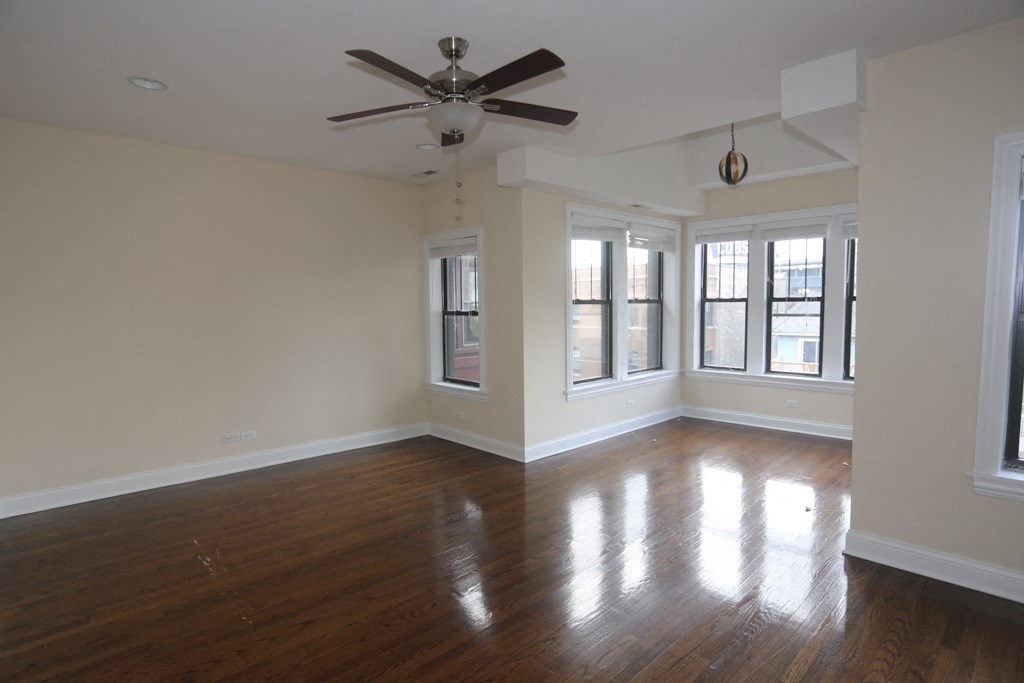 an empty living room with a ceiling fan and windows