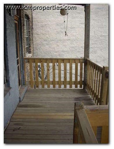a porch with a wooden railing and a window