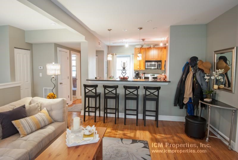 a living room and kitchen with a couch and chairs