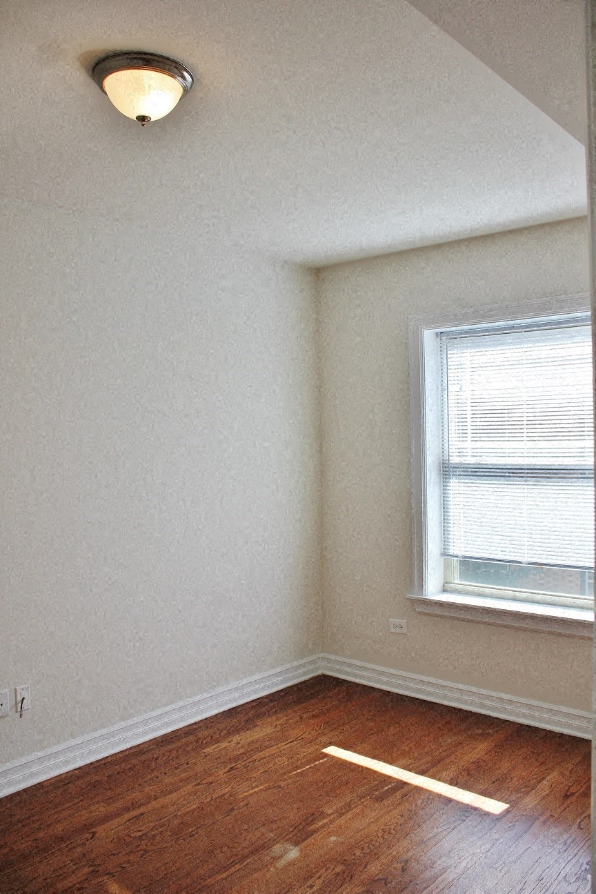 an empty room with a window and a wooden floor