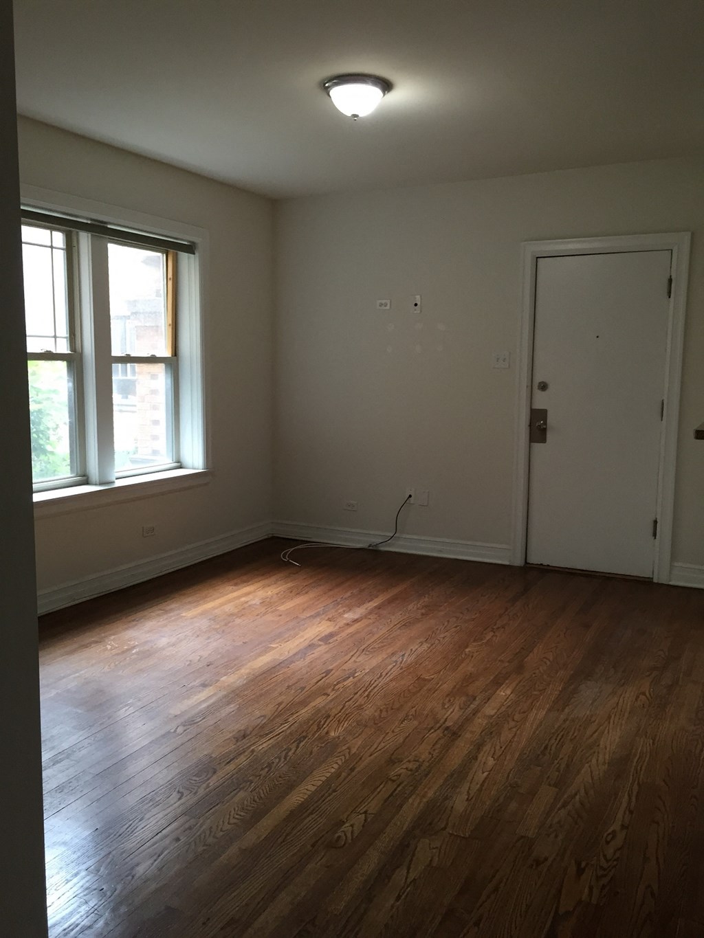 an empty living room with wood floors and a window