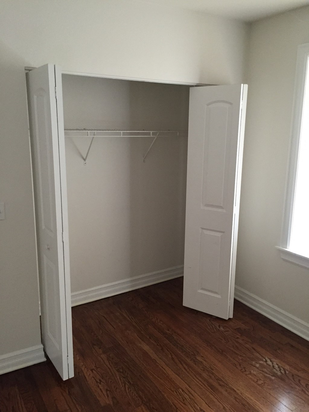 an empty closet in a room with wooden floors and a door open to a closet