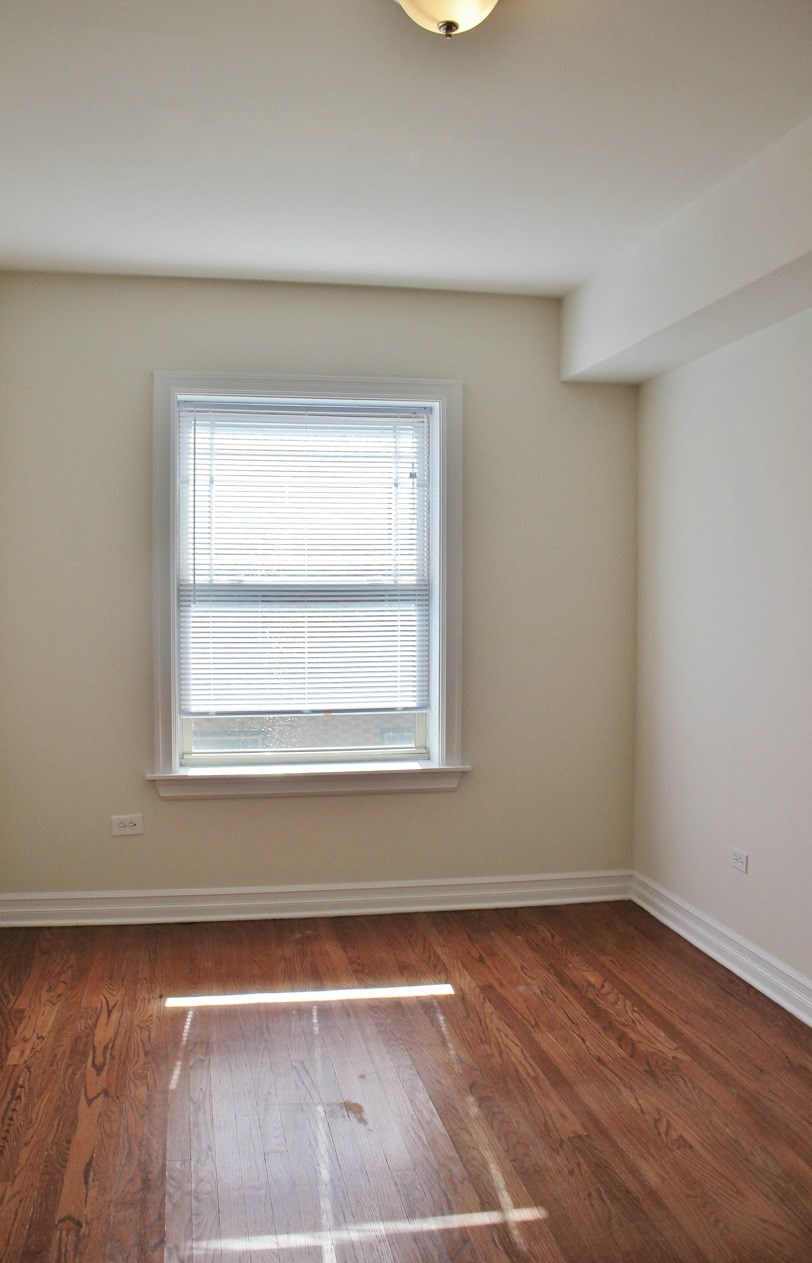 an empty room with a window and wooden floors
