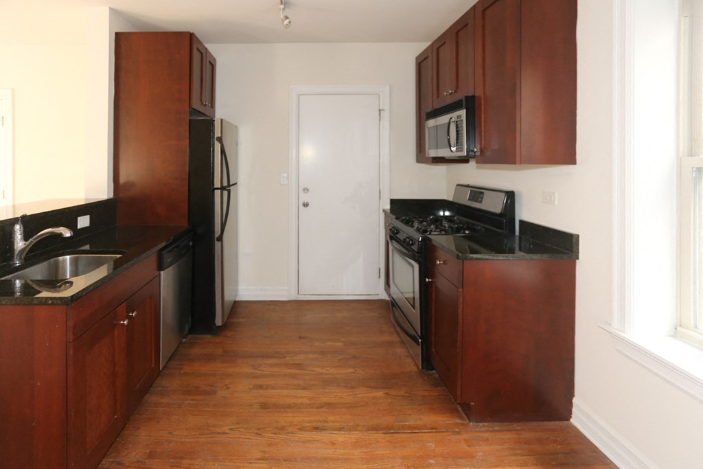 an empty kitchen with wooden cabinets and stainless steel appliances