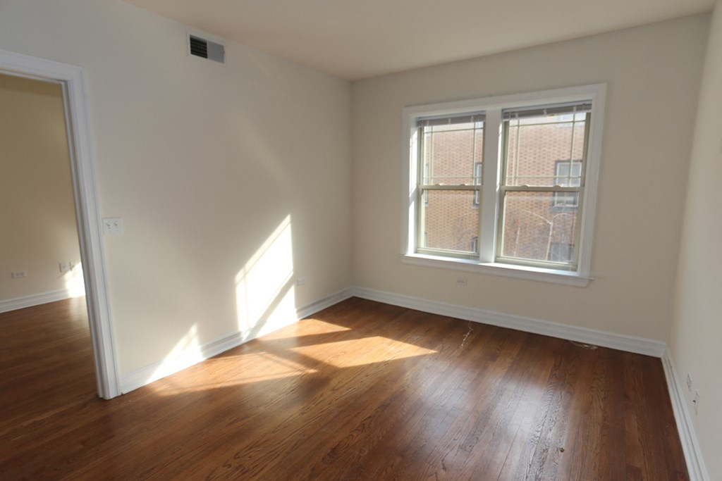 an empty room with wooden floors and a window