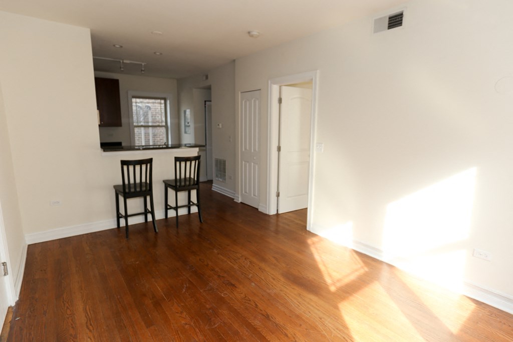 an empty living room with wooden floors and a kitchen