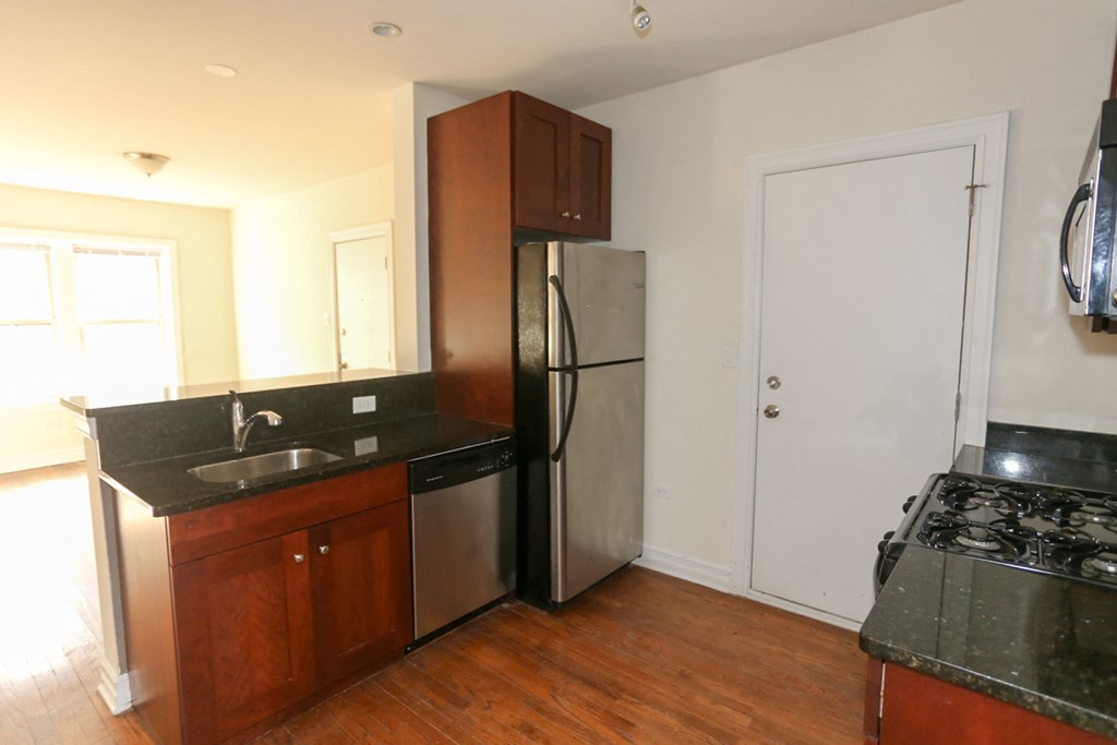 an empty kitchen with a stainless steel refrigerator and sink