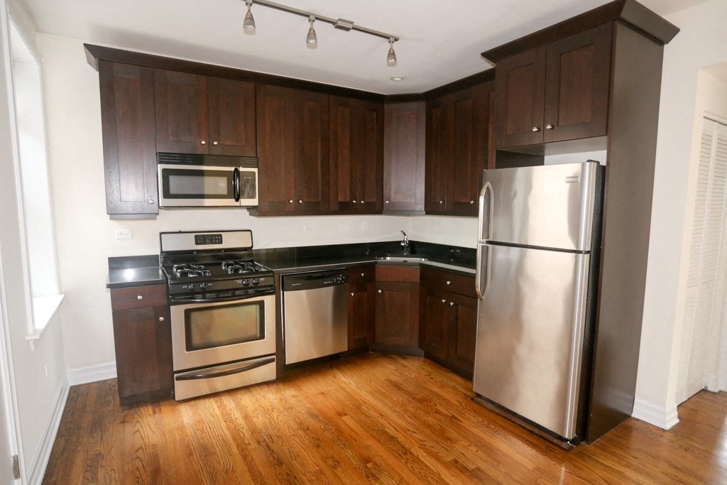 an empty kitchen with wooden cabinets and stainless steel appliances