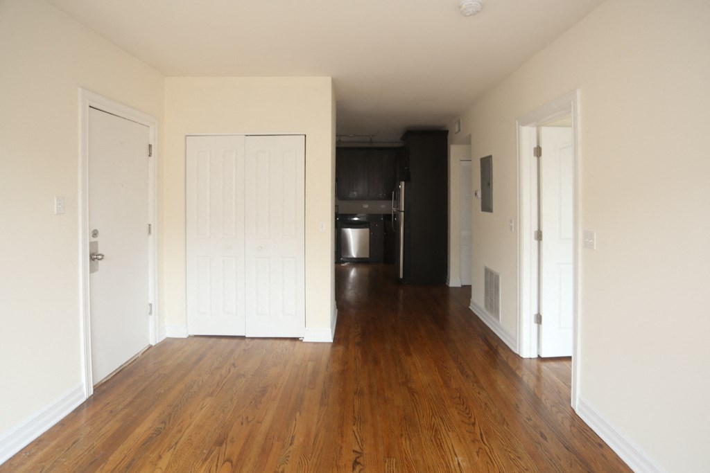 an empty living room with wood floors and white walls