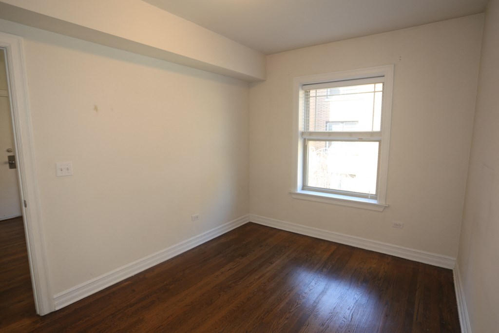 an empty room with wooden floors and a window