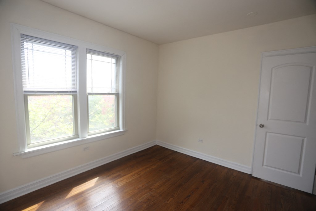 an empty room with wooden floors and two windows