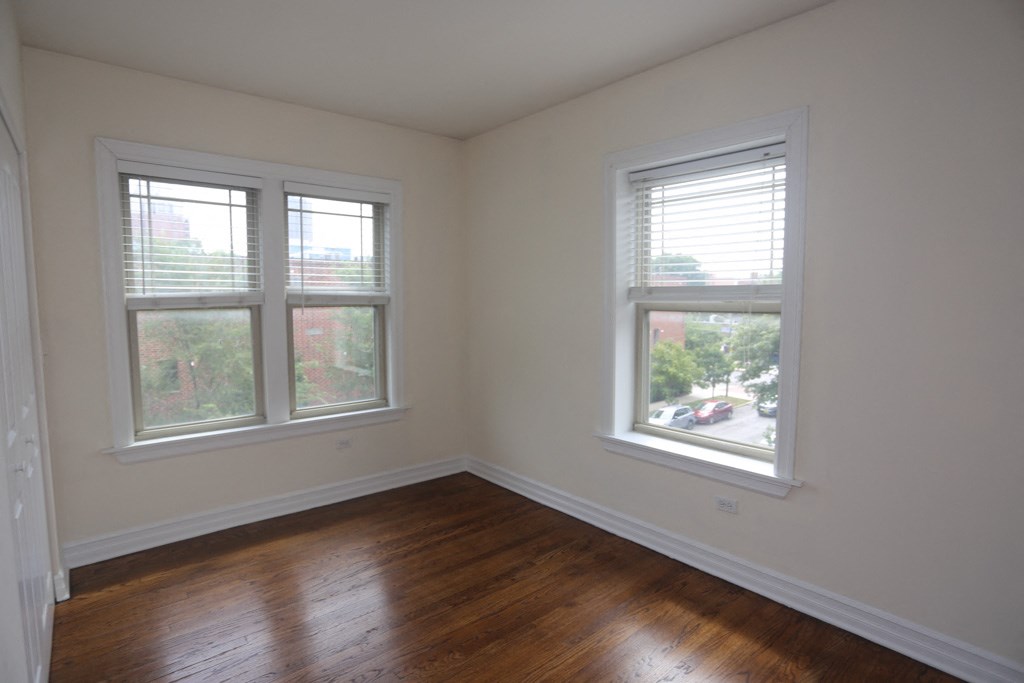 an empty room with wooden floors and two windows