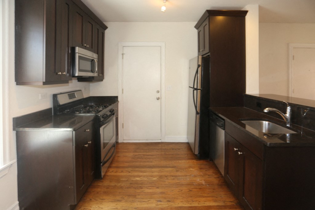 an empty kitchen with black cabinets and stainless steel appliances