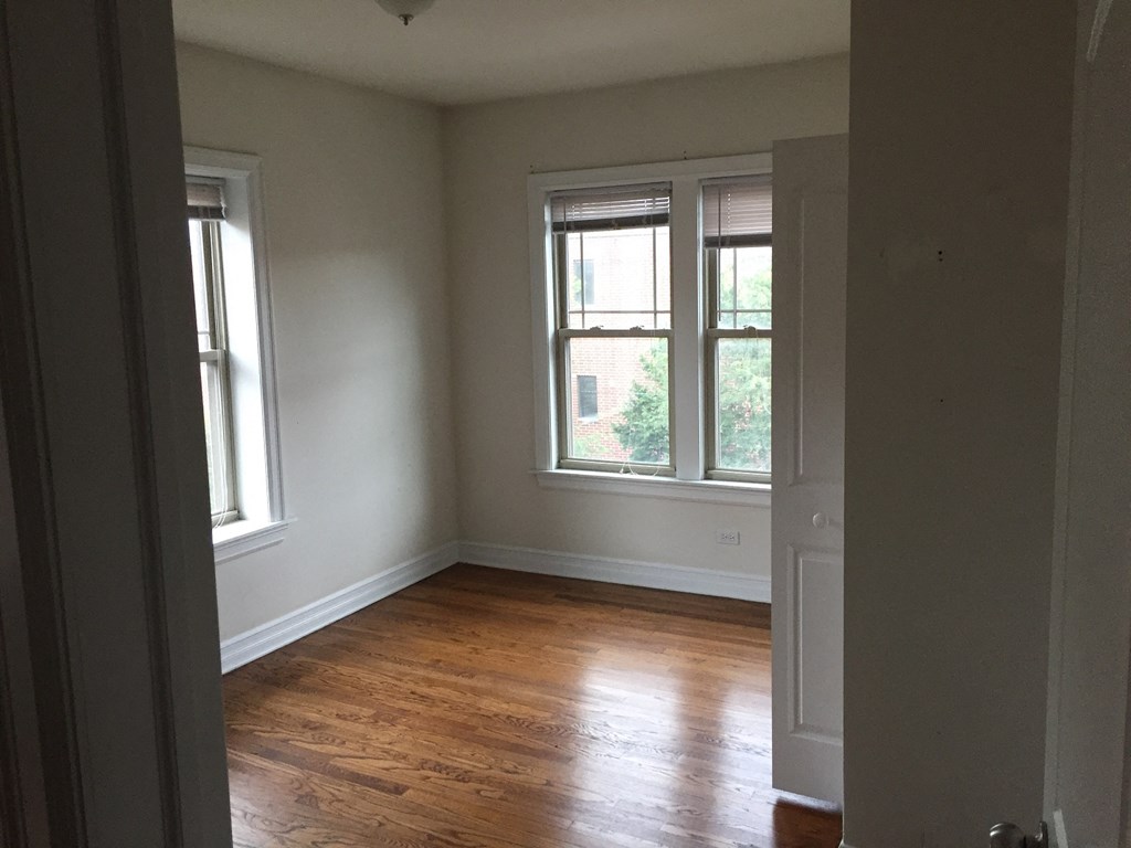 an empty room with a wood floor and three windows