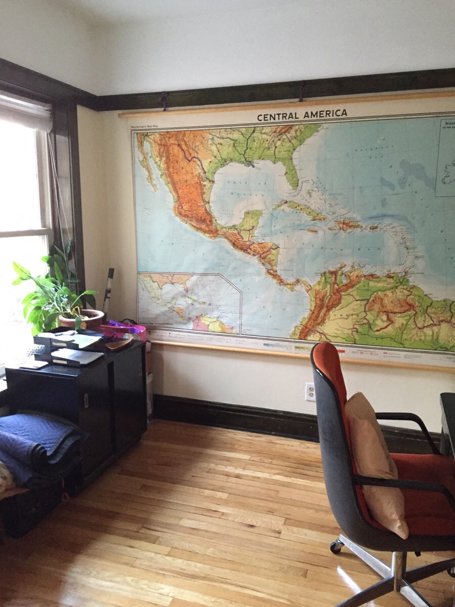 a room with a map of central america on the wall and an office chair