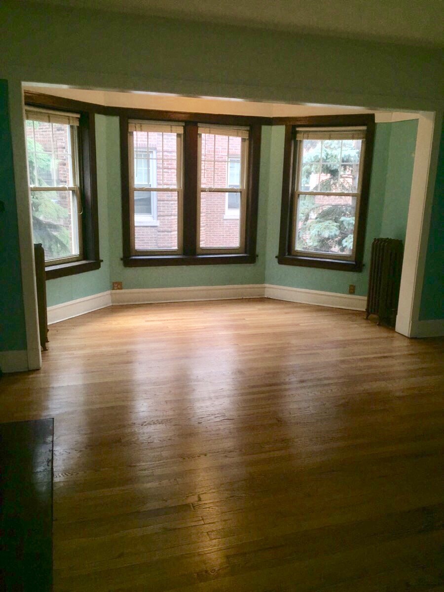 an empty living room with a hard wood floor and three windows