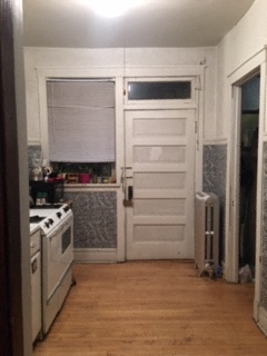 a small kitchen with a stove and a white door
