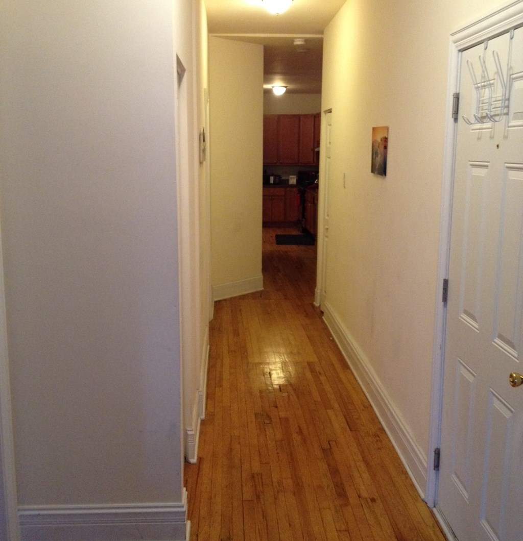 a hallway with a hard wood floor and white walls